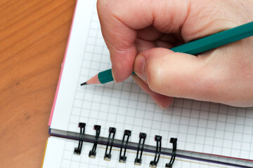 Writing notes in a structured notebook with a green pencil
