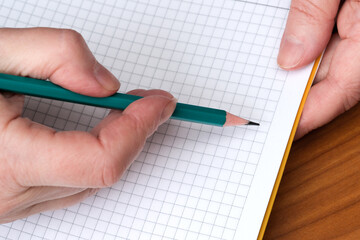 Creating a plan with a pencil on graph paper in a bright workspace