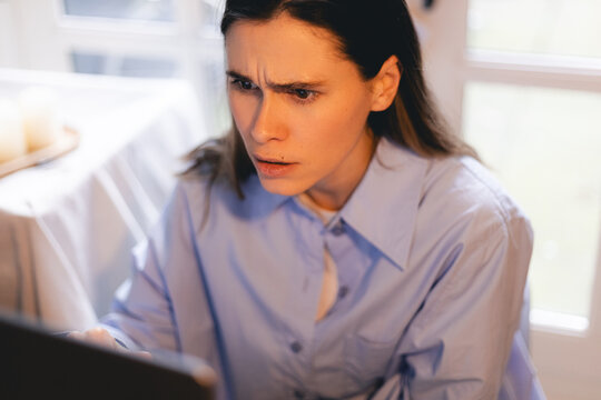 Pensive sad millennial woman employee responsible manager spending time at office desk frowning looking at pc screen unable to find correct decision answer wrestling with difficult hard problem.