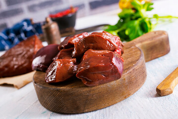 Raw Beef liver meat on wooden board with peppers