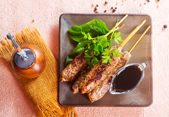 Grilled Lula kebab on skewers with spices in a claim plate on a table