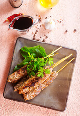 Grilled Lula kebab on skewers with spices in a claim plate on a table