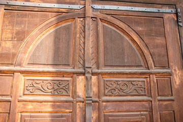 Old wooden gate with arched windows and carved panels creating a vintage and rustic look reflecting...