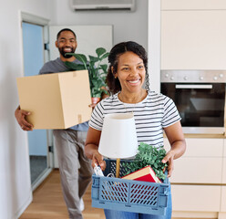 Young black couple moving into a new modern house, carrying boxes and arriving home together....