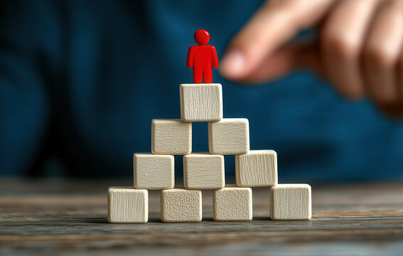 A red figurine atop a pyramid of wooden blocks, signifying leadership or success
