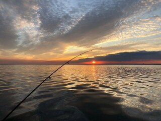 evening fishing in the sea from a boat, beautiful seascape with setting sun and dramatic clouds