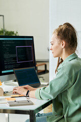 Young adult Caucasian woman sitting at desk working on neural network development using desktop...