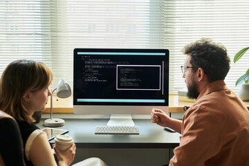 Caucasian young adult woman and Caucasian middle aged man collaborating at desk, analyzing neural...
