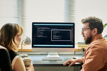 Caucasian young adult woman and Caucasian young adult man collaborating at desk, analyzing neural...