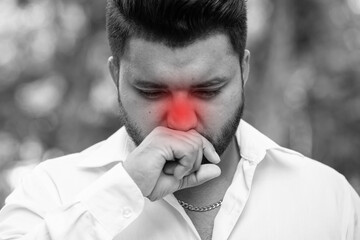 Unwell South Asian young adult man having cold, flu with allergic runny nose, nasal viral infection, dust allergy, air pollution, bad smell, stinky pungent smell, with dangerous red alert effect