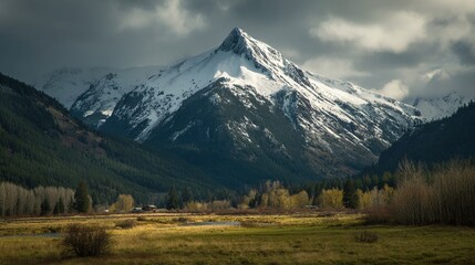 Fototapeta premium Snowy mountain peak above a valley, autumn colors