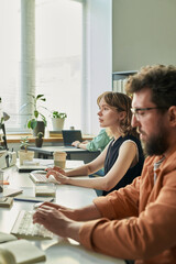 Caucasian young adult woman and Caucasian middle aged man developing neural network on desktop...