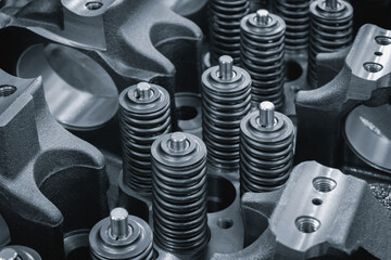 Dark blue close-up of engine valve springs. springs are black and shiny. mage has an industrial and...