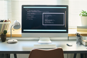Modern workspace showing large desktop monitor displaying neural network development code on...