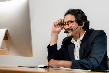 Happy office employee wearing headphones, enjoying a virtual meeting at his modern workstation.