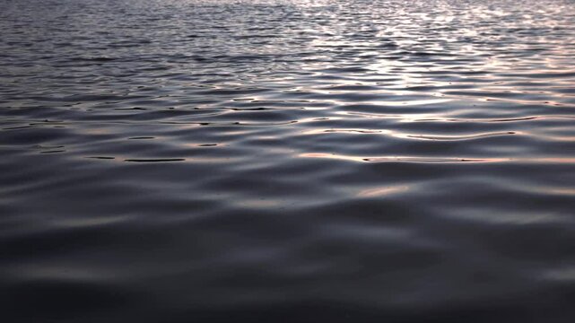 Soothing footage of gentle waves rippling across a calm river surface. Shot without visible shoreline, this seamless water texture is ideal for use as a natural background, meditative loop, or peacefu