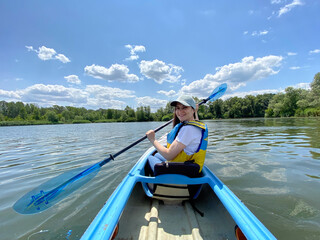 Happy woman in kayak with paddle, summer day, kayaking on the river.