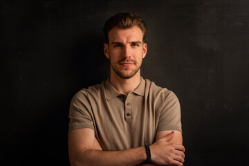 Portrait of a handsome young man standing against isolated black background
