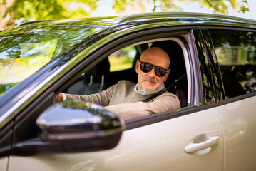 Middle aged man sitting in a car and driving in the city