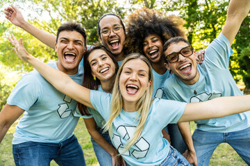 Multi ethnic group of volunteers cleaning up a forest together - Happy team of environmental activists smiling at camera outdoors - Environmental protection and non profits organization concept