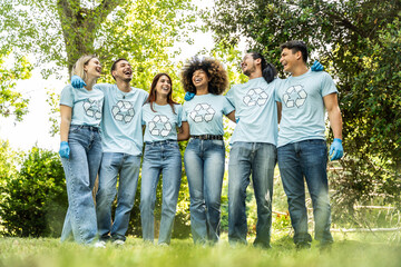 Multi ethnic group of volunteers cleaning up a forest together - Happy team of environmental activists smiling together outdoors - Environmental protection and non profits organization concept
