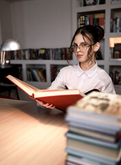 A girl in the library with a book.