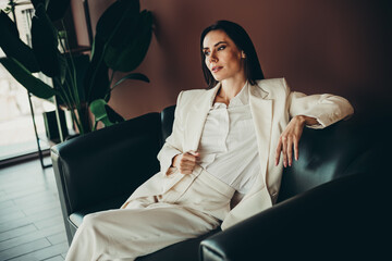 Beautiful businesswoman relaxing in stylish formalwear on a leather chair in a modern office...