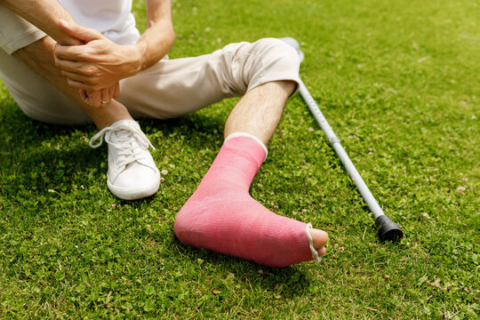  Man with broken leg in plaster during football match - injury of young athlete 