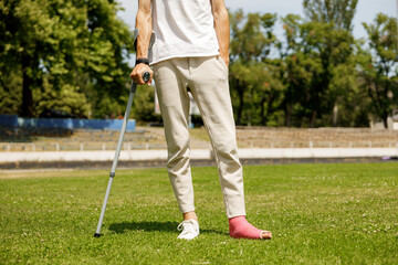 Man with broken leg in plaster during football match - injury of young athlete 