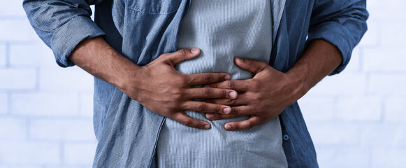 Unrecognizable Black Guy Touching Aching Abdomen Having Painful Stomachache Standing Over Gray...