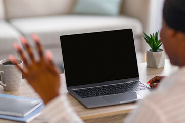 Unrecognizable black woman having video chat with young man on laptop while staying home, back view, copy space. African american lady having job interview online, waving at pc screen