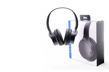close up of black wireless stereo headphones and paper box on white background