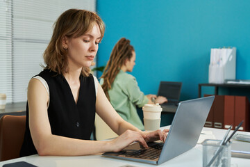 Caucasian young adult woman working on laptop developing neural network in modern office,...