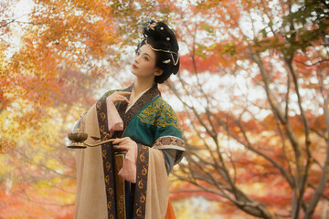Graceful female in traditional attire among autumn leaves Chinese word means autumn.