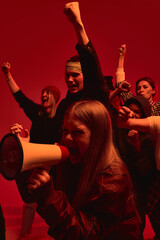 Demonstrators lift their hands in defiance and vocalize support for human rights, illuminated by...