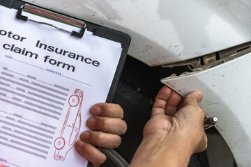 Close up unknown car insurance agent man checking damage lists on car claim document 