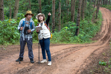 Asian male bird watcher with binocular and female trekker trekking in national forest