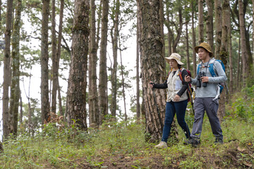Obraz premium Asian male bird watcher and female trekker trekking in national forest