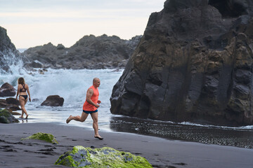 Man running on the black sand beach