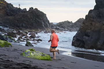 Man running on the black sand beach