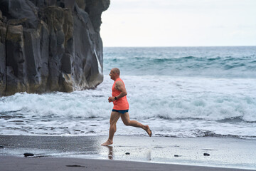 Man running on the black sand beach