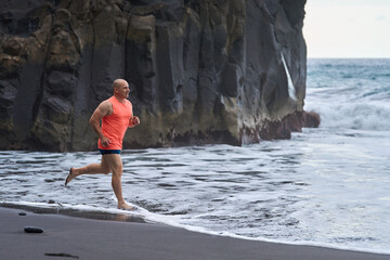 Man running on the black sand beach