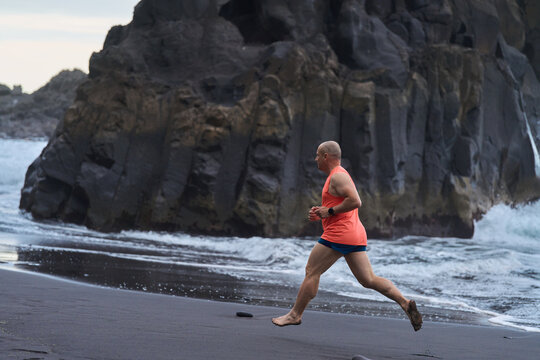 Man running on the black sand beach
