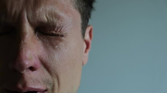 Tear rolling down a man's cheek. Close up of Crying man with tears in eye