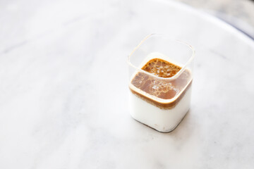 Cup of milk dirty coffee on white marble table by the window.