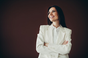 Beautiful professional businesswoman in white formalwear posing with arms crossed and smiling,...