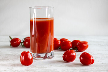 Tomato juice. Cherry tomato. White wood texture table.
