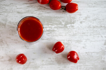 Tomato juice. Cherry tomato. White wood texture table.