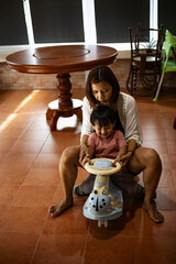 Mother And Toddler Riding A Toy Car In The House