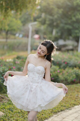 Young Asian woman in a floral dress enjoying a sunny day.